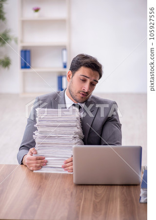 Young male employee and too much work in the office 105927556