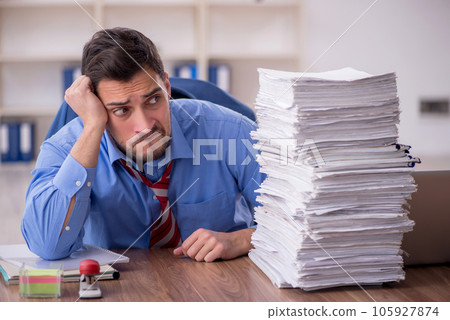 Young male employee unhappy with excessive work in the office 105927874