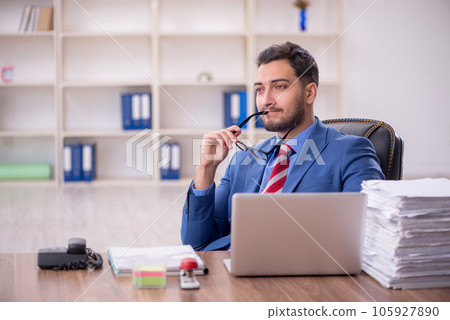 Young male employee unhappy with excessive work in the office 105927890