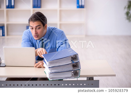 Young male employee and too much work in the office Young male employee and too much work in the office 105928379