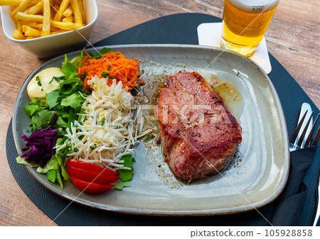 Belgian varkens cote de los, baked pork steak with fries, salad and beer Belgian varkens cote de los, baked pork steak with fries, salad and beer 105928858