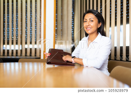 Portrait of friendly businesswoman at negotiation table in office Portrait of friendly businesswoman at negotiation table in office 105928979
