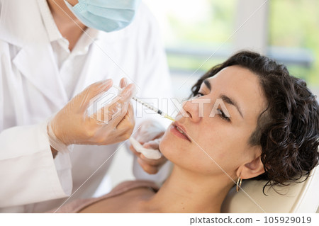 Woman getting procedure of injection contouring and for facial correction in clinic 105929019