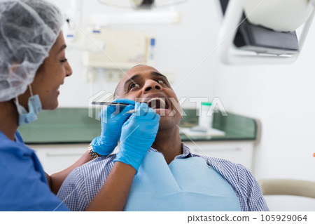 Man sitting with open mouth during dental checkup at dentist Man sitting with open mouth during dental checkup at dentist 105929064