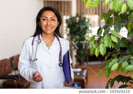 Woman doctor wear white medical uniform and stethoscope with folder of documents Woman doctor wear white medical uniform and stethoscope with folder of documents 105929210