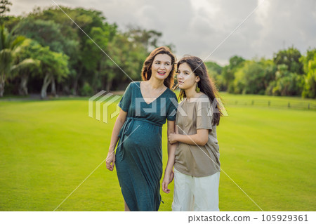 A heartwarming moment captured in the park as a pregnant woman after 40 shares a special bond with her teenage daughter, embracing the beauty of mother-daughter connection 105929361