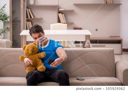 Young man with toy bear at home 105929362