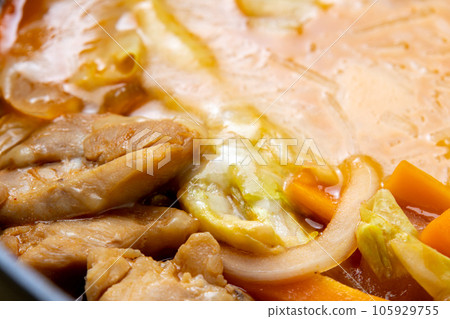 A close-up of the cooking scene of making cheese dak galbi (Korean-style stir-fried chicken and vegetables with cheese) in a frying pan. A close-up of the cooking scene of making cheese dak galbi (Korean-style stir-fried chicken and vegetables with cheese) in a frying pan. 105929755