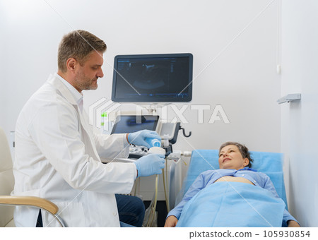 Doctor sonographer applying gel on ultrasound device before treatment with patient Doctor sonographer applying gel on ultrasound device before treatment with patient 105930854