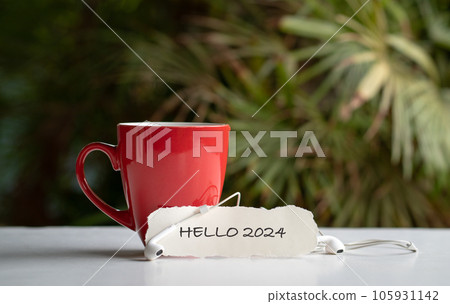 Hello 2024 on piece of paper next to cup of coffee. Hello 2024 on piece of paper next to cup of coffee. 105931142