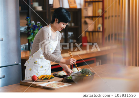 A woman in her 50s cooking in the kitchen A woman in her 50s cooking in the kitchen 105931550