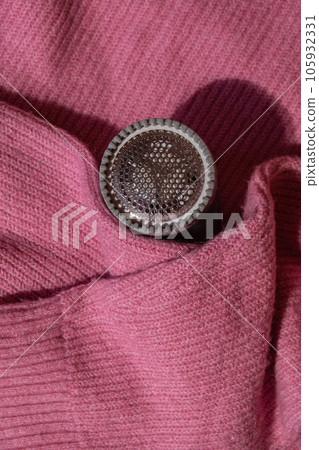 Anti-pilling razor. Device for shaving clothes. Anti-Plush fabric Shaver. Electric portable sweater pill defuzzer Lint remover from pink acrylic or wool sweater. Electric device fabric shaver after Anti-pilling razor. Device for shaving clothes. Anti-Plush fabric Shaver. Electric portable sweater pill defuzzer Lint remover from pink acrylic or wool sweater. Electric device fabric shaver after 105932331