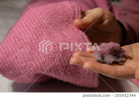 Woman using Anti-pilling razor at home. Device for shaving clothes. Anti-Plush fabric Shaver. Electric portable sweater pill defuzzer Lint remover from pink acrylic or wool sweater. Slow fashion Woman using Anti-pilling razor at home. Device for shaving clothes. Anti-Plush fabric Shaver. Electric portable sweater pill defuzzer Lint remover from pink acrylic or wool sweater. Slow fashion 105932344
