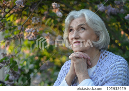 Close-up portrait of happy senior beautiful woman on background in spring park 105932659