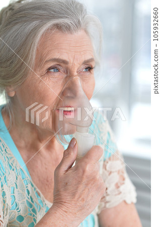Portrait of an elderly woman using an inhaler 105932660