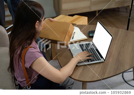 Young business woman working online e-commerce shopping at home. Young woman seller prepare parcel box of product for deliver to customer Young business woman working online e-commerce shopping at home. Young woman seller prepare parcel box of product for deliver to customer 105932869