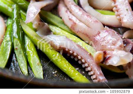 A close-up of a cooking scene in which squid (boiled squid) and garlic sprouts are fried in a frying pan. 105932879