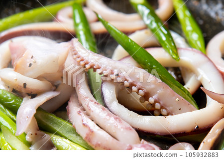 A close-up of a cooking scene in which squid (boiled squid) and garlic sprouts are fried in a frying pan. 105932883