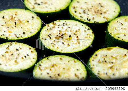 烹飪場景，在煎鍋中烘烤圓形西葫蘆片（用鹽和胡椒烤）。 105933108