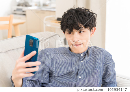 Young man frowning at smartphone 105934147
