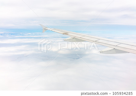 View from the airplane window at a beautiful cloudy sky and the airplane wing View from the airplane window at a beautiful cloudy sky and the airplane wing 105934285