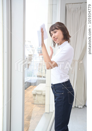 一個女人用布擦房間的窗戶 一個女人用布擦房間的窗戶 105934779