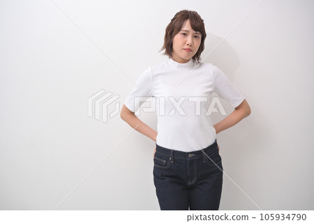 A woman standing by a white wall indoors A woman standing by a white wall indoors 105934790