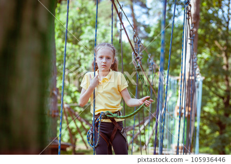 A child in a forest adventure park made of ropes. 105936446