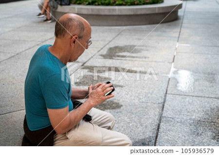 Active senior man checks cellphone on a new York City park bench Active senior man checks cellphone on a new York City park bench 105936579