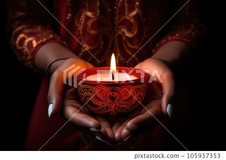 Woman hands with henna holding colorful clay diya lamps lit during diwali celebration 105937353