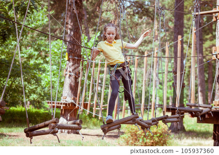 A child in a forest adventure park made of ropes. A child in a forest adventure park made of ropes. 105937360
