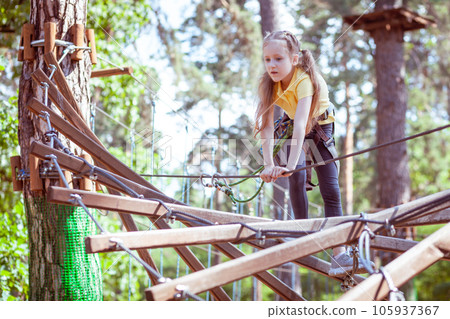 A child in a forest adventure park made of ropes. 105937367