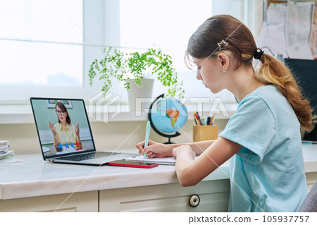 Preteen girl having video online lesson, at home using laptop 105937757