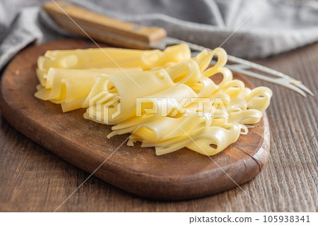 Slices of cheese on cutting board. 105938341