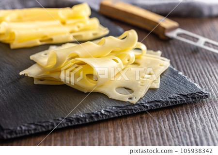 Slices of cheese on cutting board. 105938342