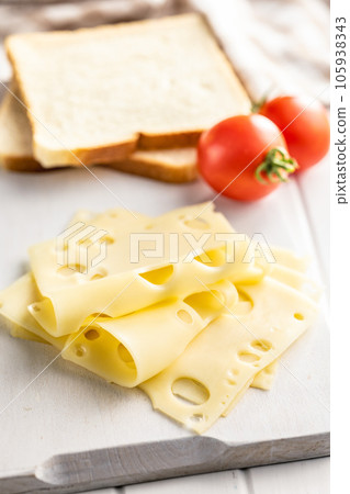 Slices of cheese on cutting board. 105938343