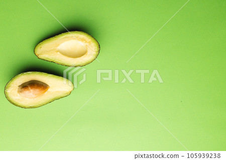 Close up of two halves of avocado and copy space on green background Close up of two halves of avocado and copy space on green background 105939238