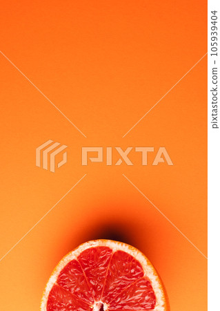 Close up of half of red grapefruit and copy space on orange background Close up of half of red grapefruit and copy space on orange background 105939404
