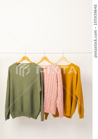 Three sweaters hanging from clothes rail with copy space on white background Three sweaters hanging from clothes rail with copy space on white background 105939648
