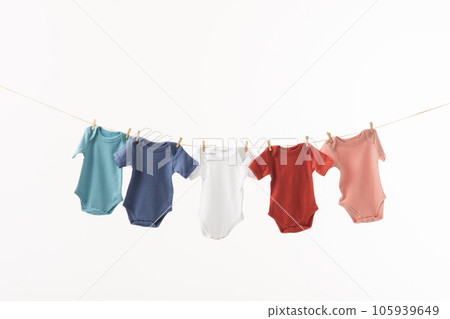 Multi coloured baby grows hanging from clothes line with pegs and copy space on white background Multi coloured baby grows hanging from clothes line with pegs and copy space on white background 105939649
