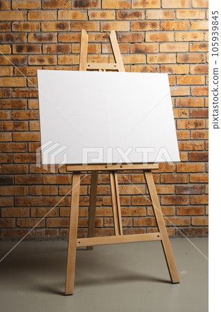 White canvas on wooden easel and copy space on brick wall background White canvas on wooden easel and copy space on brick wall background 105939845