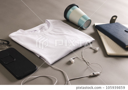 Flat lay of white t shirt, smartphone, earphones and notebooks with copy space on grey background 105939859