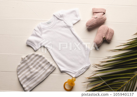 Flat lay of white baby grow, hat, dummy and pink booties with copy space on white background Flat lay of white baby grow, hat, dummy and pink booties with copy space on white background 105940137