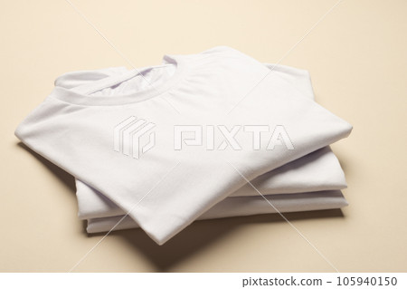 Close up of folded white t shirts and copy space on yellow background Close up of folded white t shirts and copy space on yellow background 105940150