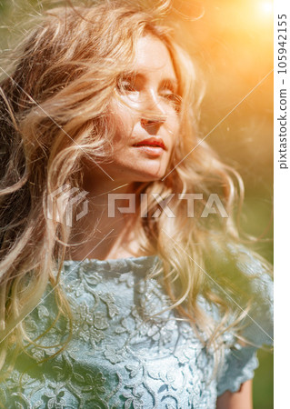 Blond garden. Portrait of a blonde in the park. Happy woman with long blond hair in a blue dress. Blond garden. Portrait of a blonde in the park. Happy woman with long blond hair in a blue dress. 105942155