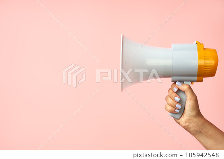 Megaphone loudspeaker in woman hands on pink background Megaphone loudspeaker in woman hands on pink background 105942548