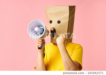 Emotional woman with paper bag on head making announcement with megaphone in hands Emotional woman with paper bag on head making announcement with megaphone in hands 105942571