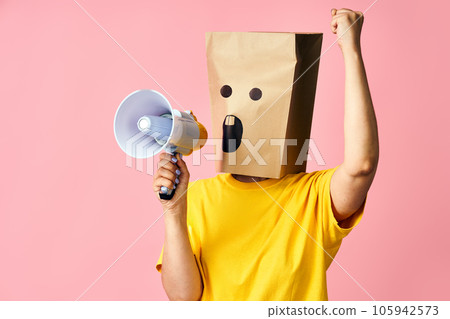 Emotional woman with paper bag on head making announcement with megaphone in hands Emotional woman with paper bag on head making announcement with megaphone in hands 105942573