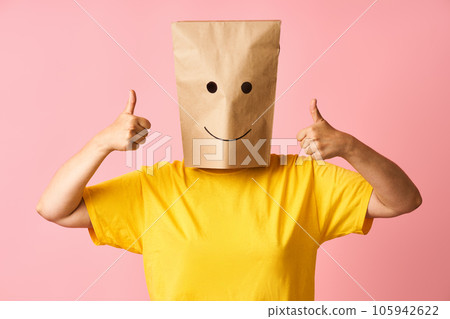 Woman wearing paper bag on head with smile emoticon icons face showing thumbs up 105942622