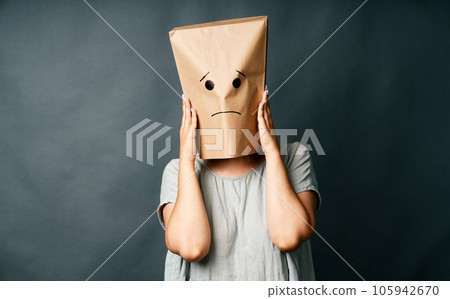 Upset woman with a paper bag on head touching temples, suffering from strong tension headache 105942670